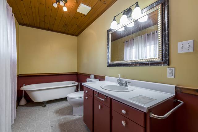 Bathroom: Clawfoot tub under a pine ceiling